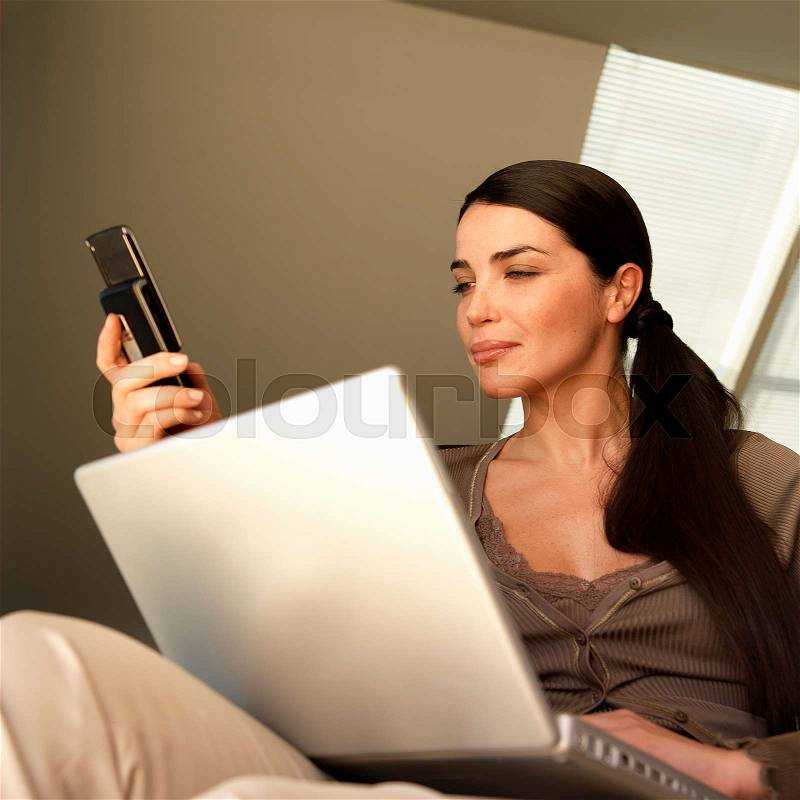 Woman with laptop and phone, stock photo