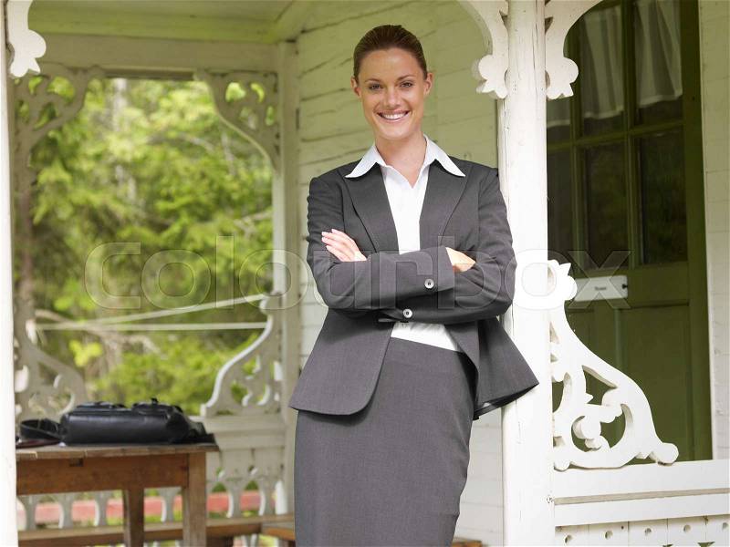 Businesswoman by country cottage, stock photo