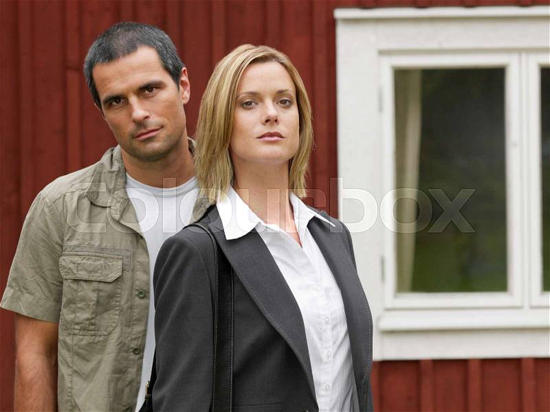 Businesswoman and man by country cottage, stock photo