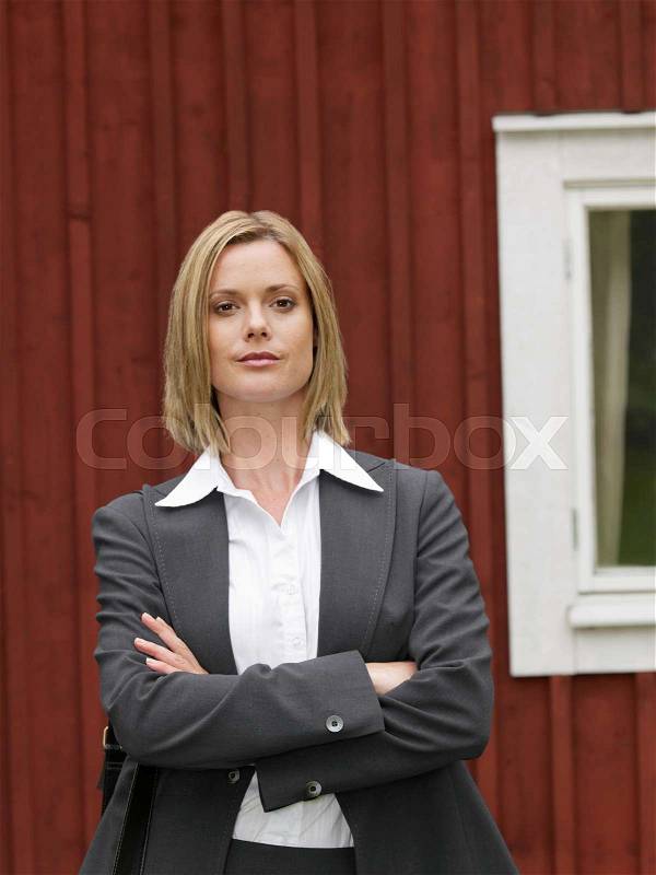 Businesswoman by country cottage, stock photo