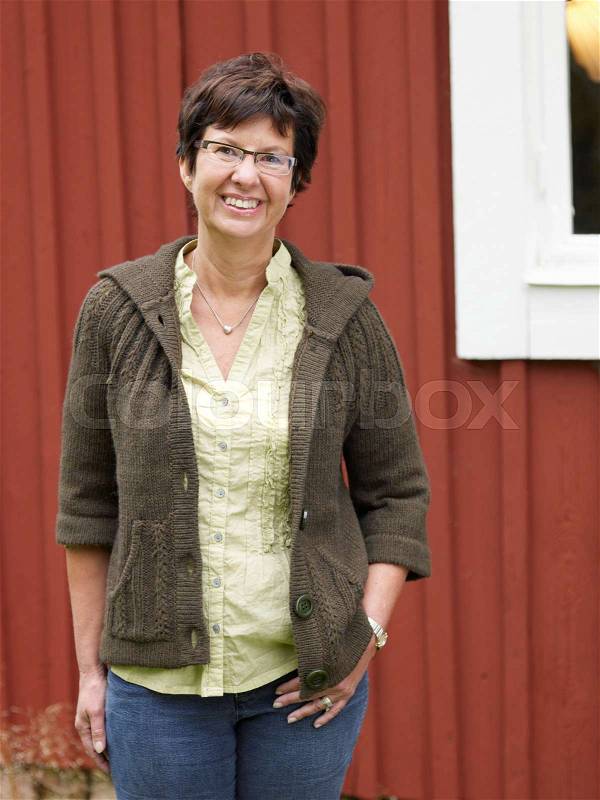 Middle aged woman by country cottage, stock photo