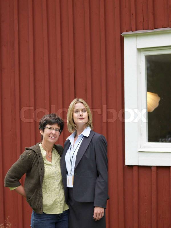 Mother and daughter outside cottage, stock photo