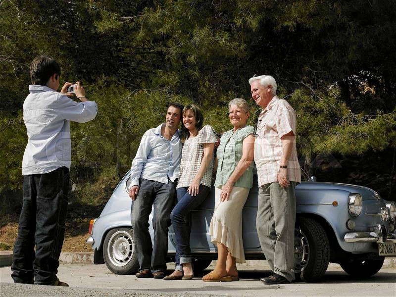Multi-generational family beside car, stock photo