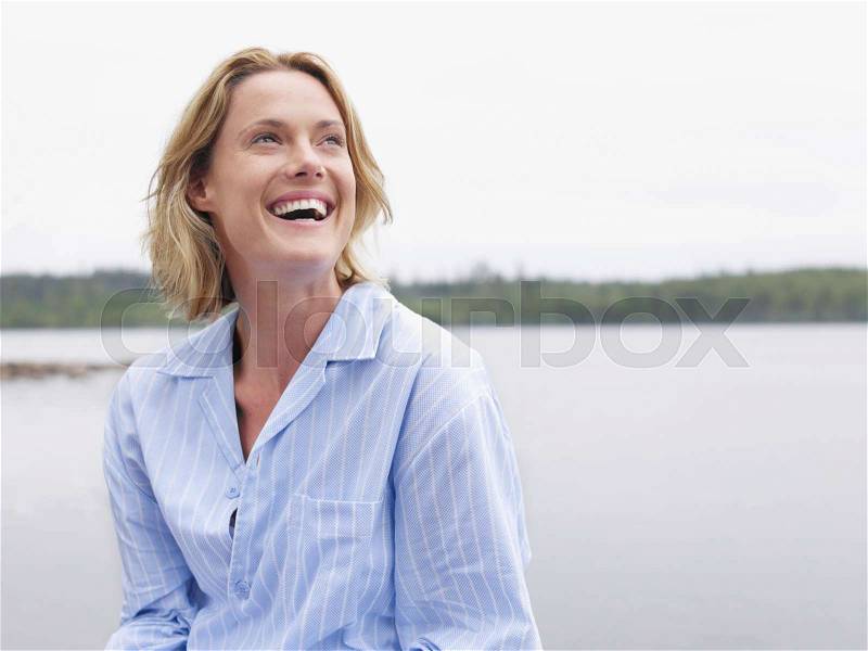 Woman laughing outdoors by the water, stock photo