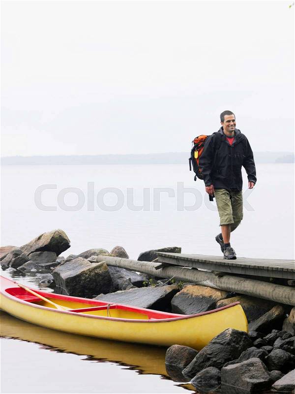 Man walking on dock near a boat smiling, stock photo