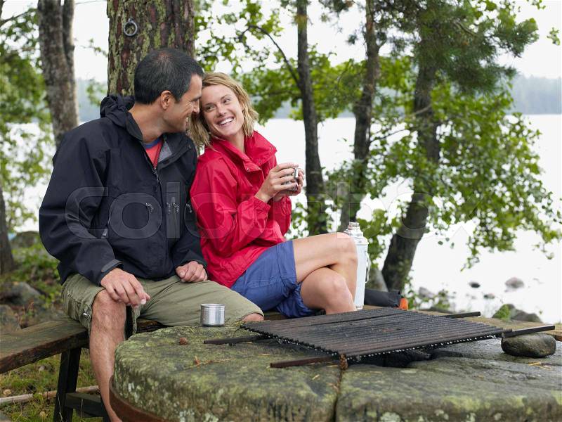 Couple sitting in a park by a fire pit, stock photo