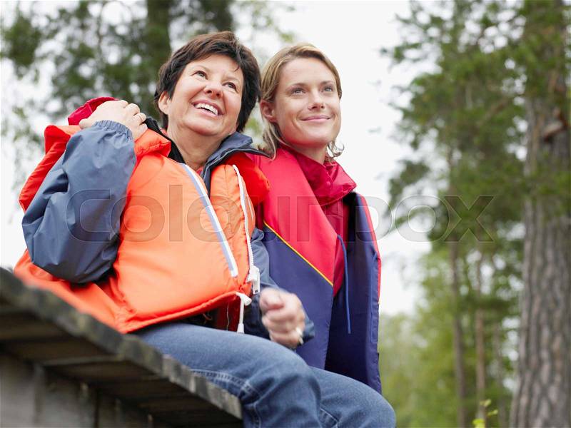 Two women on a dock wearing life jackets, stock photo