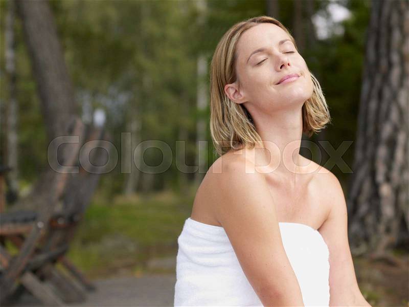 Woman wearing towel with eyes closed out, stock photo
