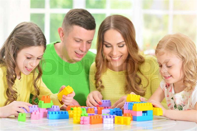 Portrait of a happy family collecting colorful blocks together, stock photo
