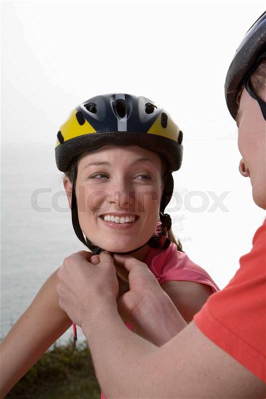 Man adjusting a Woman\'s cycle helmet, stock photo