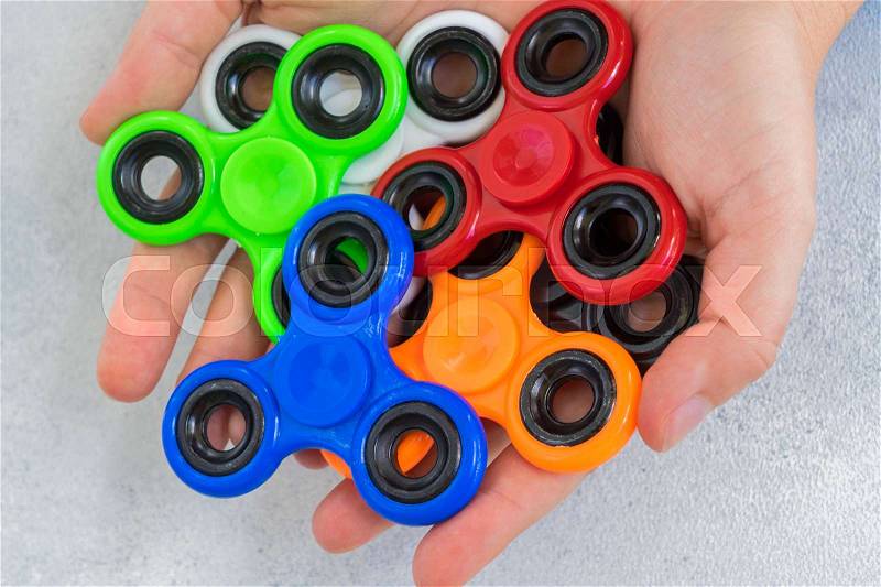 Mix of popular relaxing toy - fisget spinners - in someones open palms close up, stock photo