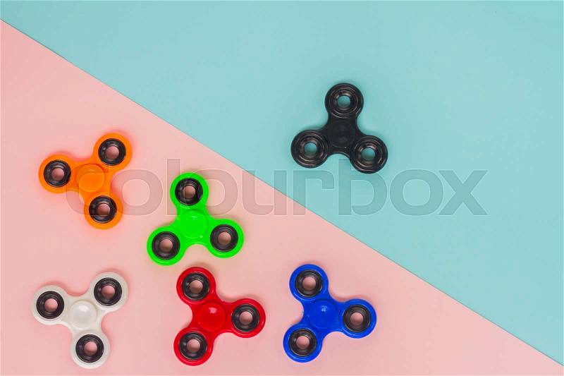 Fidget spinners on blue and pink background, popular relaxing toy, generic design, stock photo