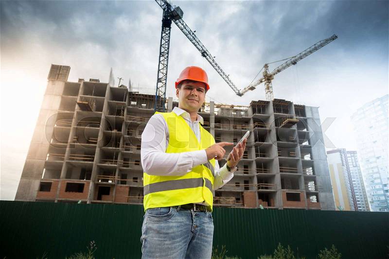 Building inspector with digital tablet on construction site, stock photo