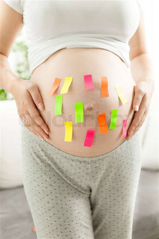 Closeup of colorful stickers on pregnant woman tummy, stock photo