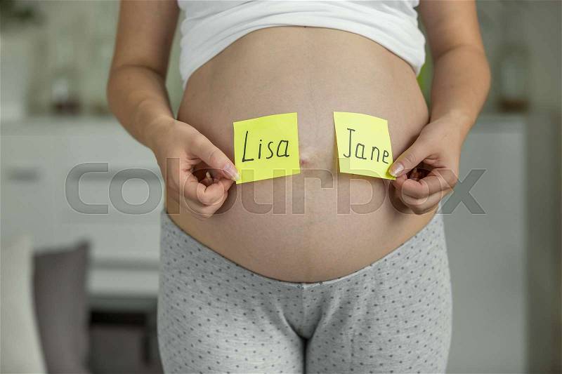 Pregnant woman choosing baby name on the stomach, stock photo
