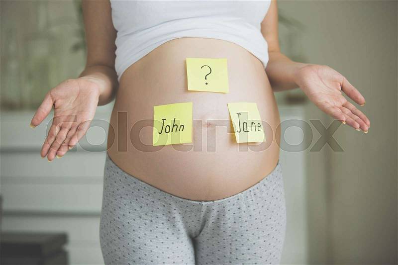 Choosing baby\'s name. Pregnant woman with names on belly, stock photo