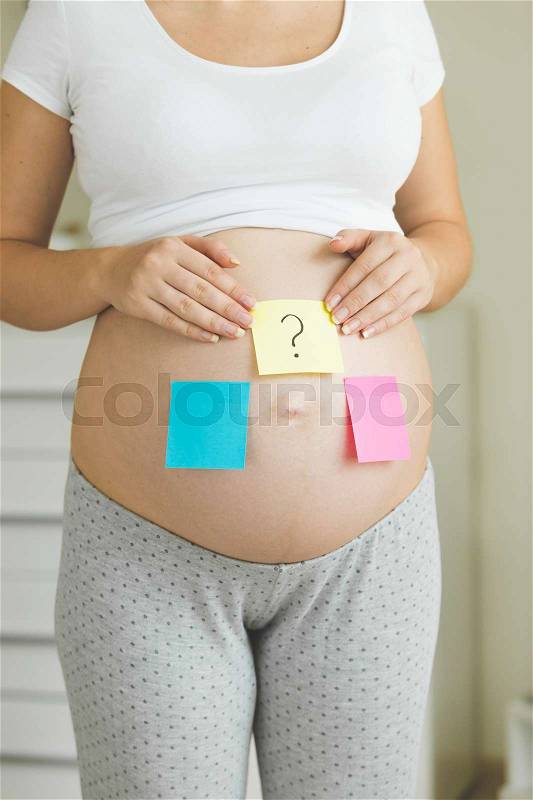 Conceptual photo of pregnant woman thinking of future baby gender, stock photo