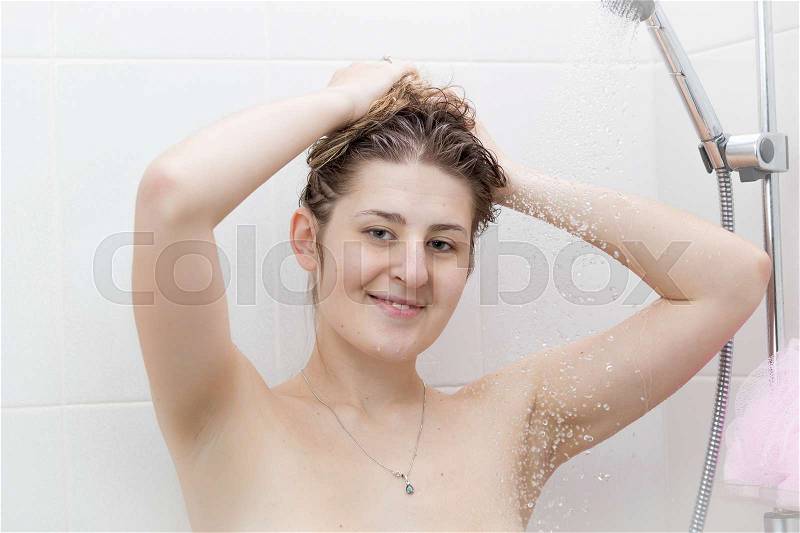 Portrait of beautiful smiling woman washing hair at shower, stock photo