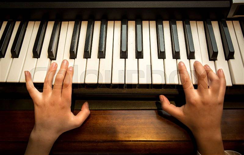 Closeup photo of child\'s hands playing on the piano, stock photo