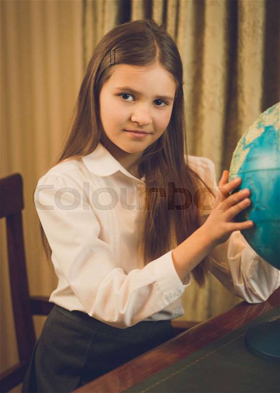 Beautiful schoolgirl posing at cabinet with Earth globe, stock photo