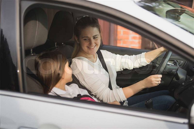 Portrait of young mother driving her daughter to school, stock photo