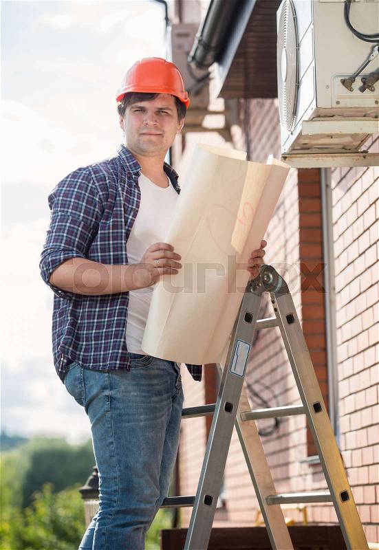 Engineer examining air conditioning system and comparing it with plan, stock photo