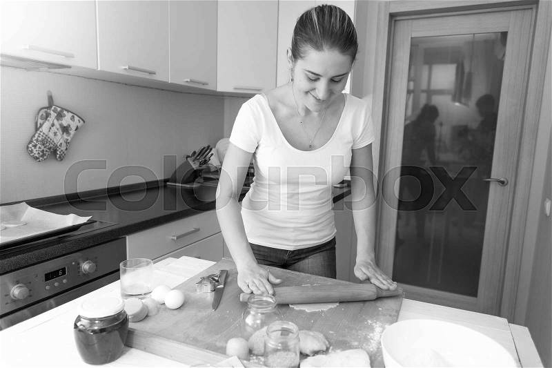Black and white image of woman making dough in kitchen, stock photo