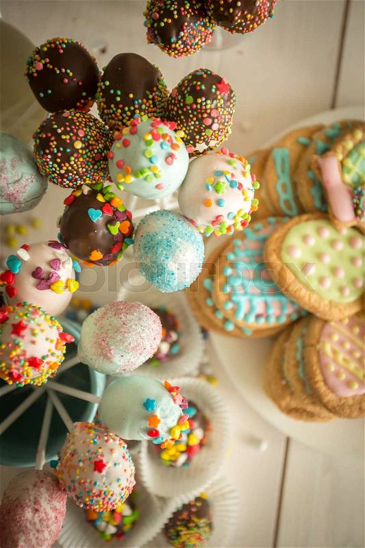Decorated candies, cake pops and cookies on white wooden desk, stock photo