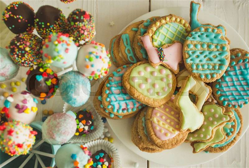 Beautiful decorated cake pops and cookies for Easter on table, stock photo