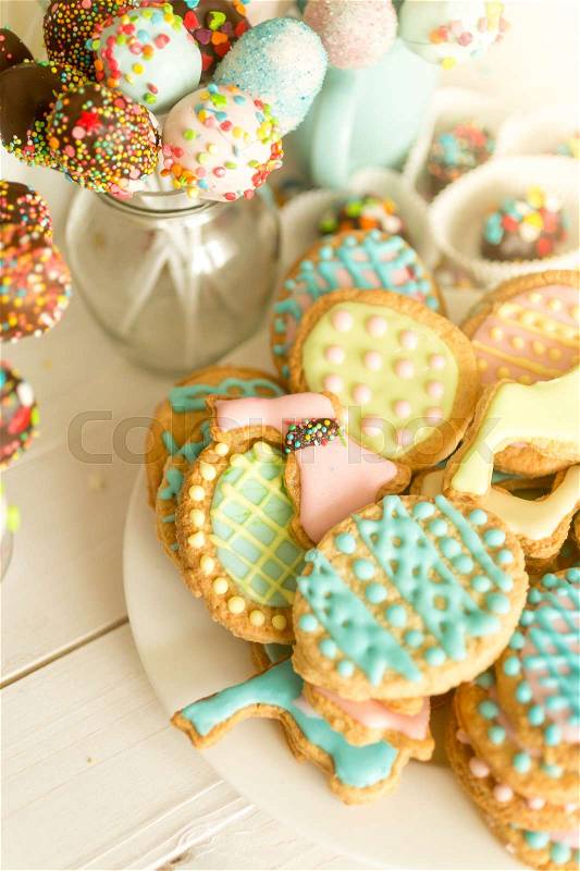 Colorful cake pops and cookies on white wooden desk, stock photo