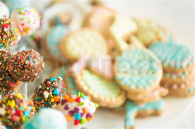 Background with colorful cookies and cake pops on white wooden desk, stock photo