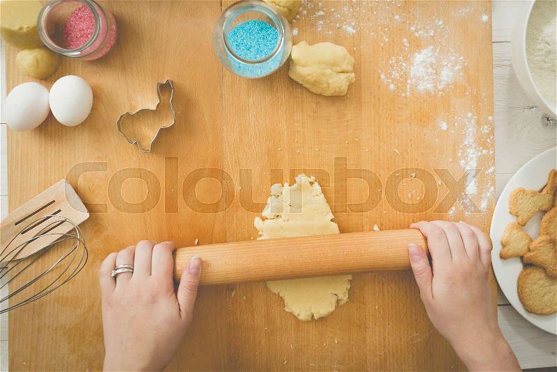 Young woman rolling dough on wooden board, stock photo