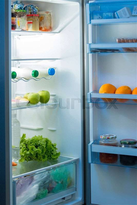 Open refrigerator on kitchen at night, stock photo