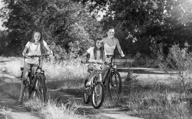 Black and white image of happy family cycling at meadow, stock photo