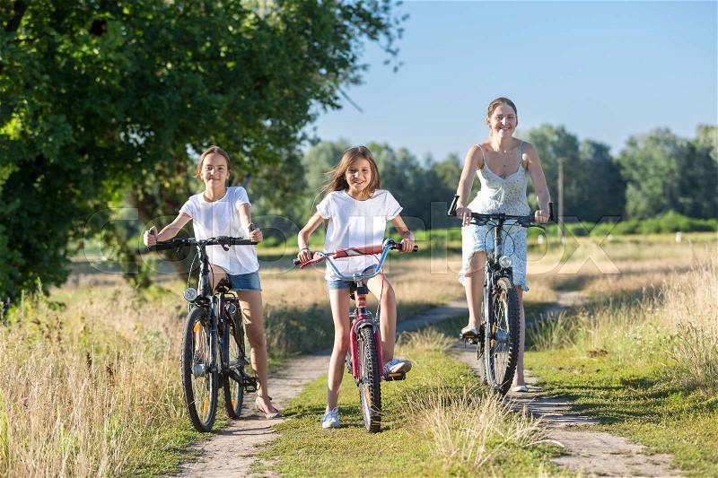 Happy young mother riding on bicycles with two daughters, stock photo