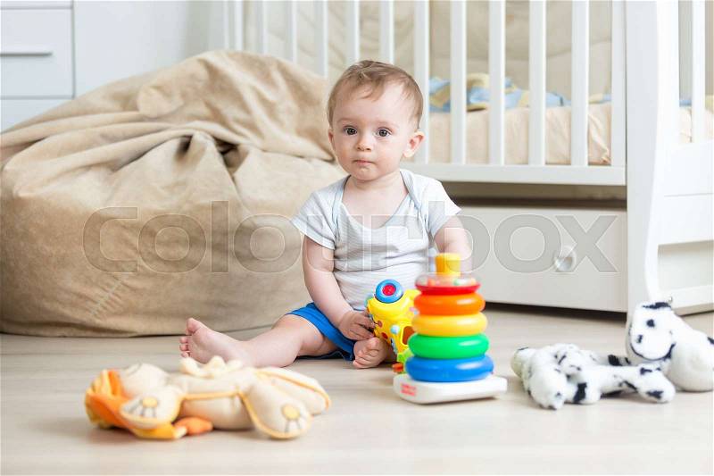 10 months old baby boy playing with colorful toy tower, stock photo