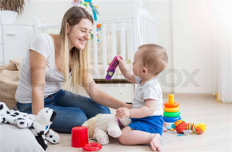 Young mother and her baby playing with to cell phone, stock photo