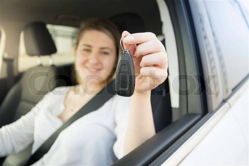 Closeup photo of young woman driving car and showing car keys, stock photo