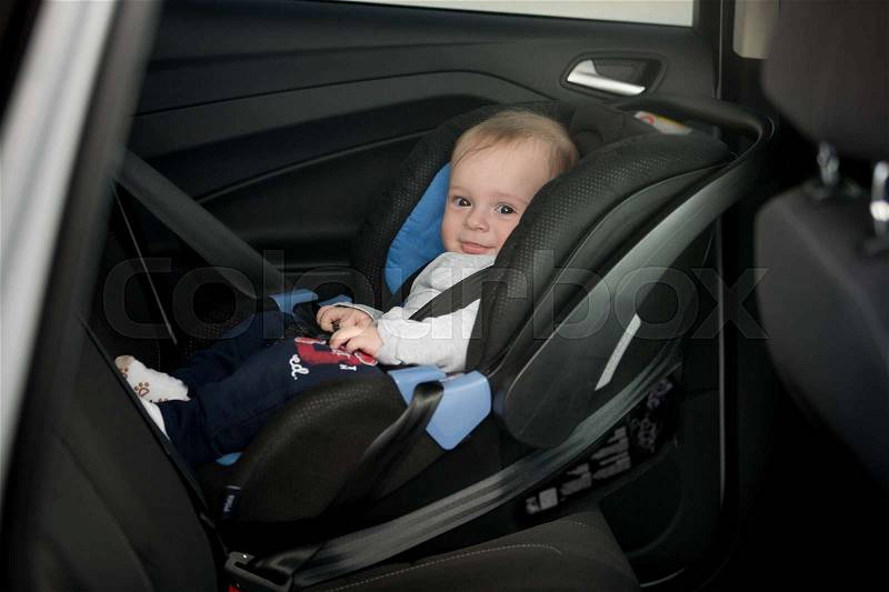 Little smiling baby on back seat, stock photo