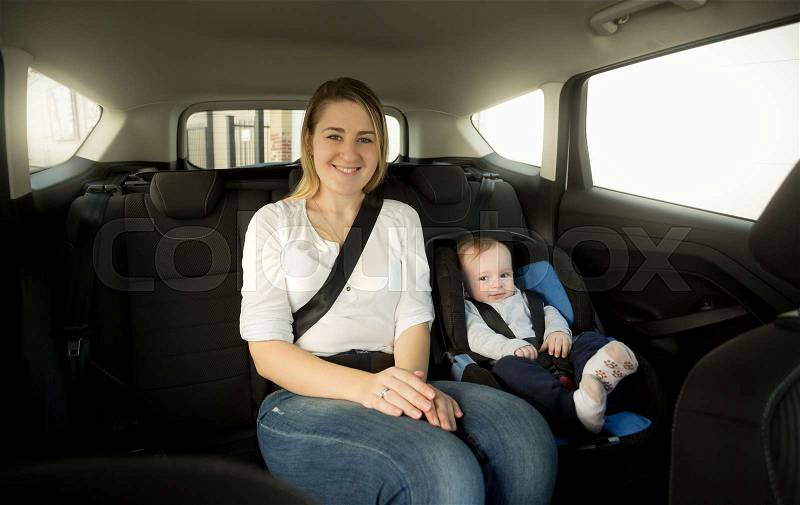 Happy smiling mother with her baby on back seat, stock photo
