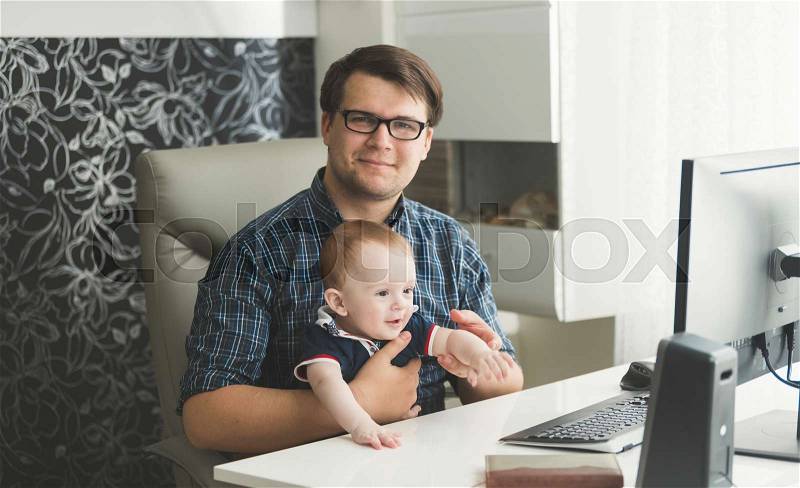 Father with his baby son working at office, stock photo