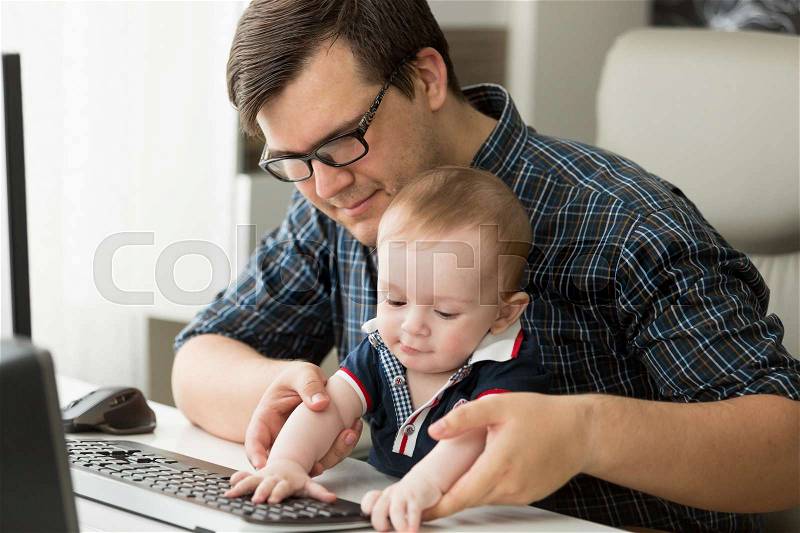 Father working at home with his little baby boy, stock photo