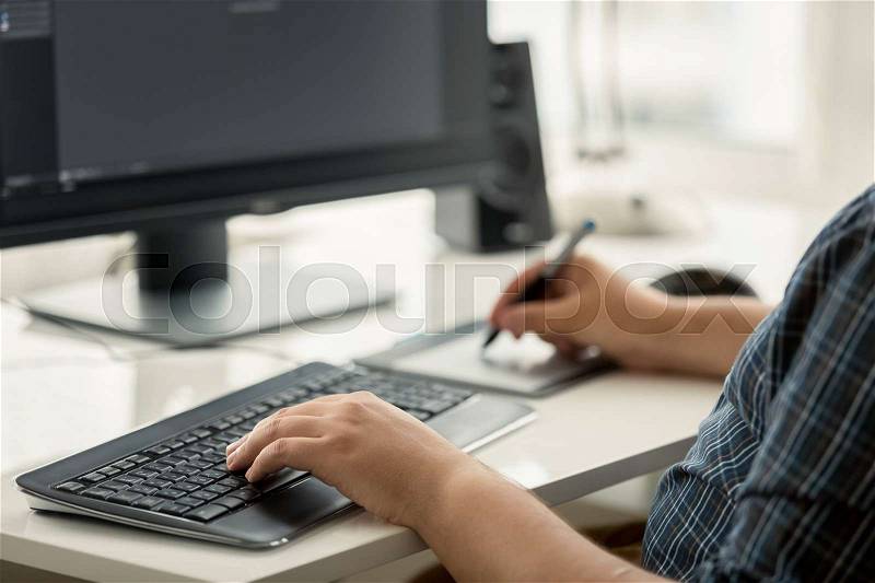 Toned photo of graphic designer using tablet and keyboard at work, stock photo