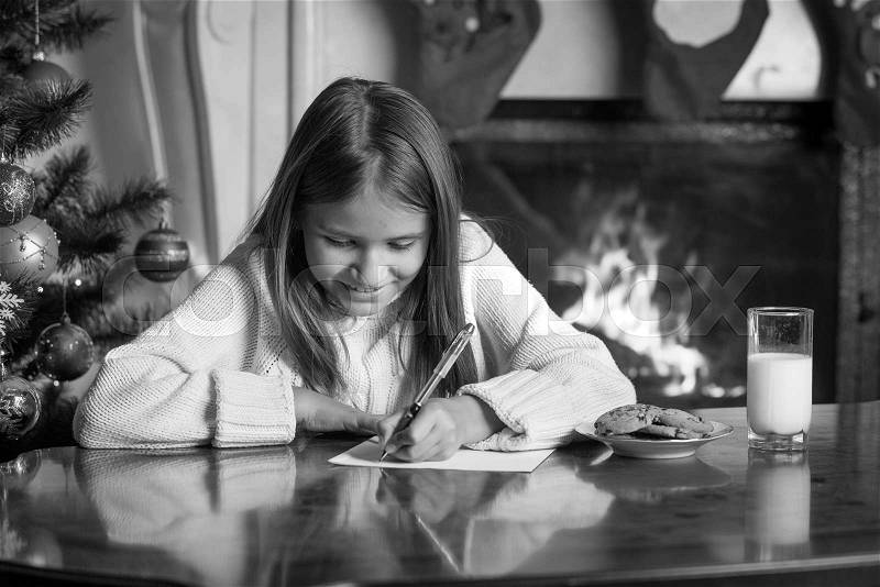 Black and white portrait of cute girl writing letter to Santa, stock photo