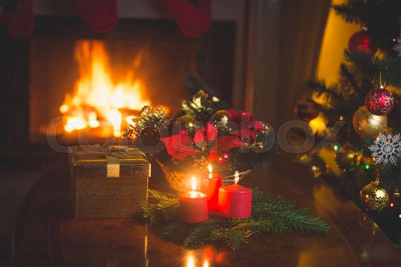 Christmas wreath with red candles in living room with burning fireplace, stock photo