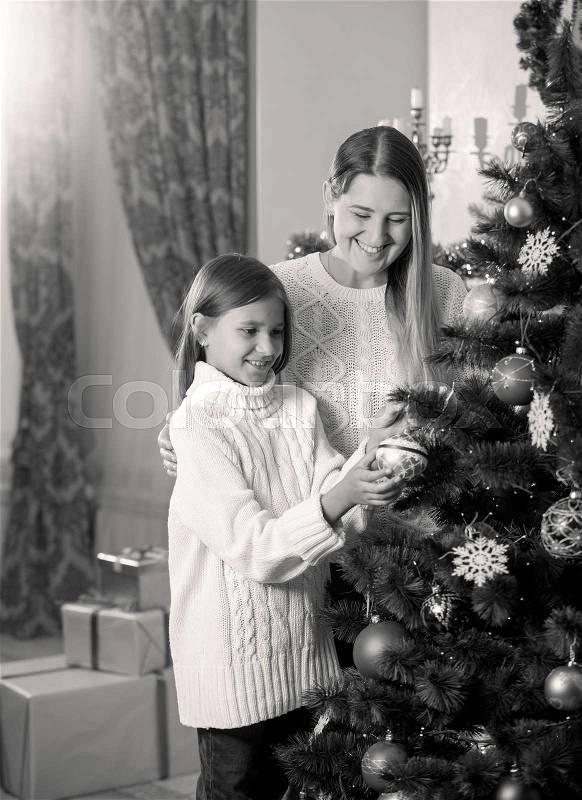 Black and white image of daughter helping mother in decorating Christmas tree, stock photo
