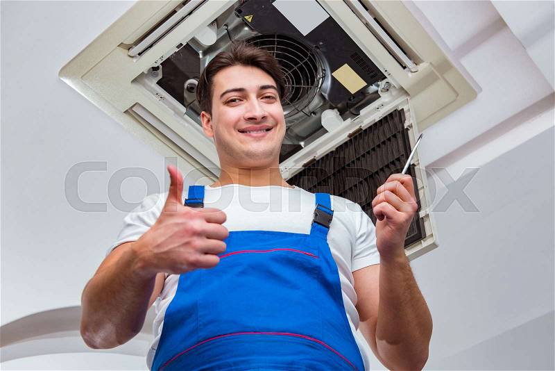 Worker repairing ceiling air conditioning unit, stock photo