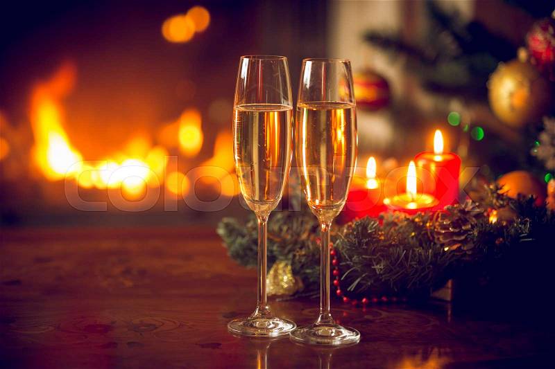 Beautiful Christmas background with two champagne flutes, burning fireplace and wreath with candles. Beautiful Christmas background, stock photo