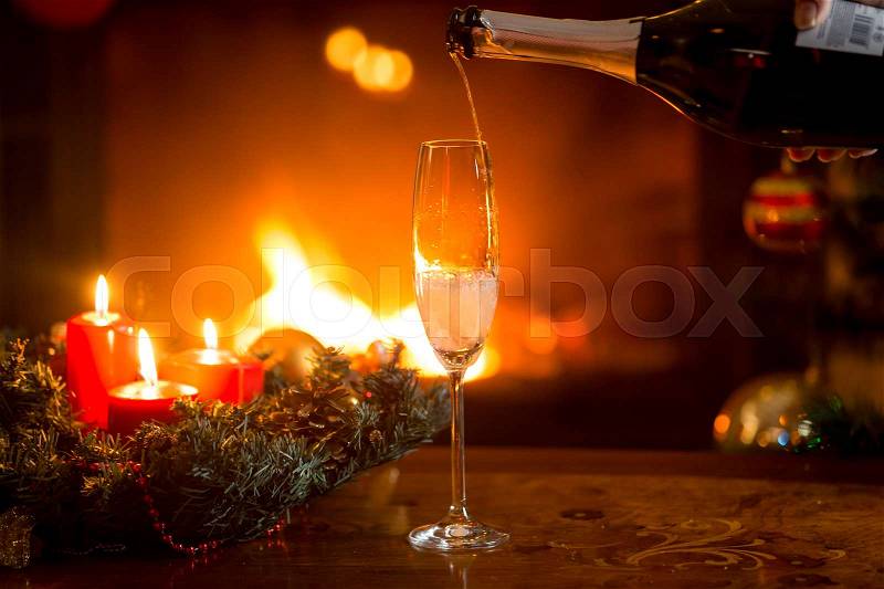 Closeup image of pouring fizzy champagne in crystal glass on table, stock photo
