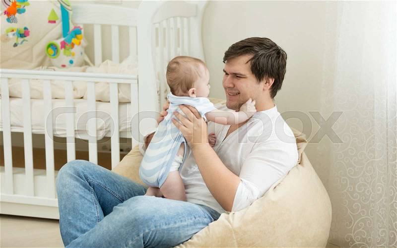 Happy young man playing with his baby at bedroom, stock photo